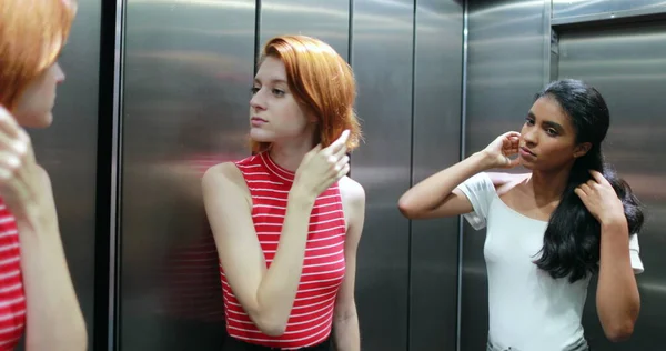 Karışık Irk Güzel Genç Kadınlar Asansör Aynasında Kendilerine Bakıyorlar — Stok fotoğraf