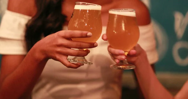 Two female friends toasting with draft beers