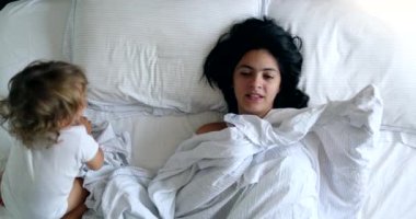 Mother and baby in morning bed playing together, waking up. top view