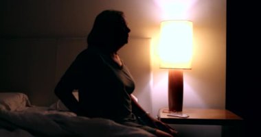 Woman going to sleep, turning nightstand light OFF