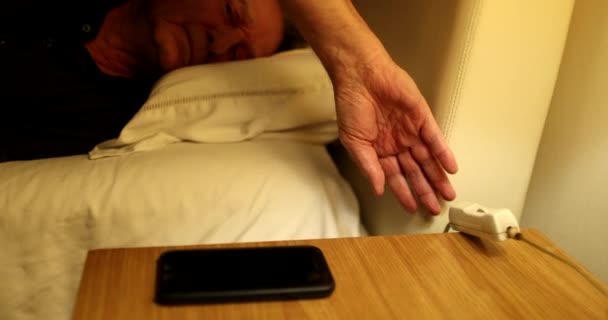 Man Turns Nightstand Light Picks Cellphone Person Checking Smartphone Screen — Stockvideo