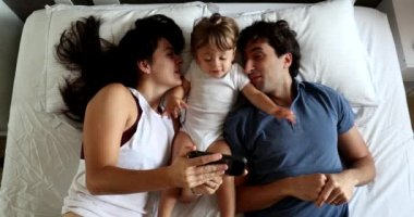 Couple in bed with infant toddler baby boy, top view