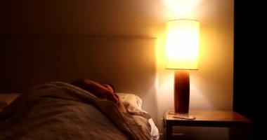 Person turning nightstand light on. Senior woman waking up in the middle of the night suffering from insomnia.