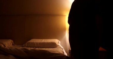 Woman sitting on the side of th ebed preparing to go to sleep