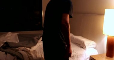 Older man lying down in bed at night turning off nightstand lamp light OFF, person going to sleep