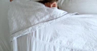 Adorable baby hiding under bed blanket. Playful One year old toddler infant plays peekaboo
