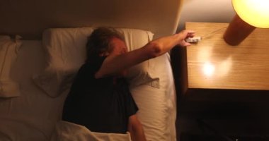 Person waking up at night, turning bedside light ON, man stretching and getting up from bed