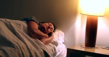 Tired older woman turning nigthstand light ON and getting up from bed