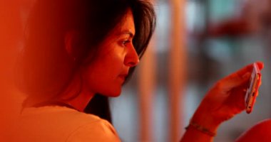 Woman looking at cellphone device at night. person watching video on phone