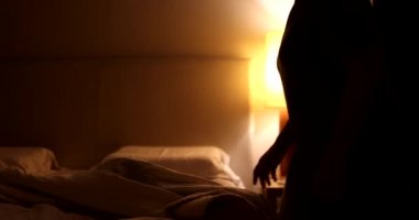 Pensive older woman sits by the side of the bed preparing to go to sleep