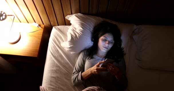 Woman Lying Bed Turns Smartphone Bedside Nightstand Lamp — Stockvideo