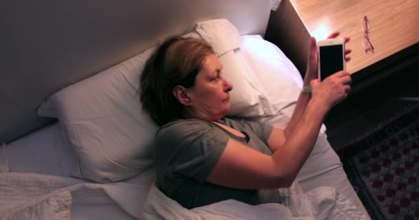 Woman Turns Cellphone Switches Nightstand Light Lamp — Stock videók