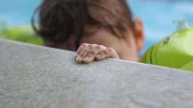 Küçük bebek havuz başında, küçük bir el destek ünitesine tutunuyor.