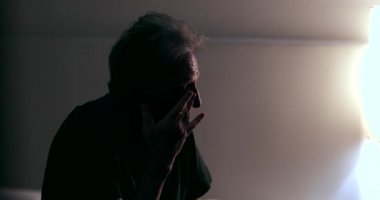 Candid tired older man rubbing eye with hand feeling sleepy