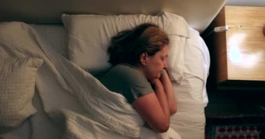 Senior woman resting in bed turning light off
