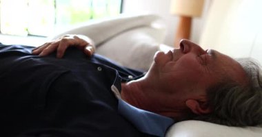 Senior man lays down in bed to sleep. Older person napping resting