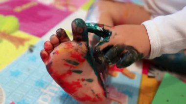 Toddler baby painting own foot with painting