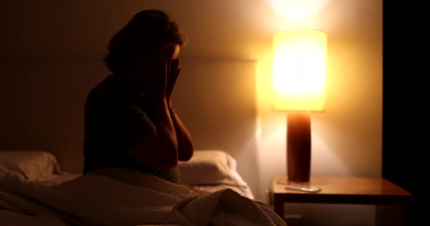 夜にベッドの横に座っている高齢者の女性が不安から苦しんで眠ることができないことを心配 — ストック動画