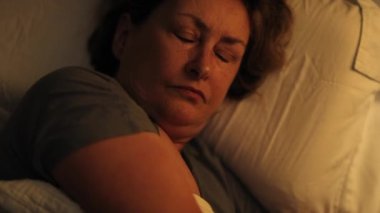 Tired sleepless older woman lying in bed unable to sleep