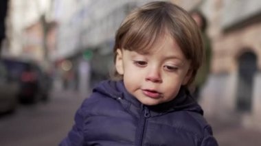 Baby toddler running in sidewalk during winter outside. Infant sprinting in city