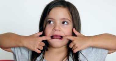 Little girl grimacing, sticking ongue out. Child grimace making funny faces