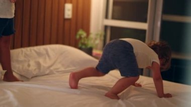 Happy toddler boy jumping on bed. Kids jump up and down