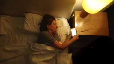 Older woman turns night lamp off and goes to sleep