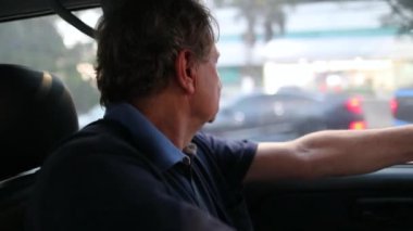 Older man driving in city. Senior person in 60s driver close-up face