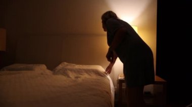 Single older woman lying in bed under blanket at night, lady going to sleep