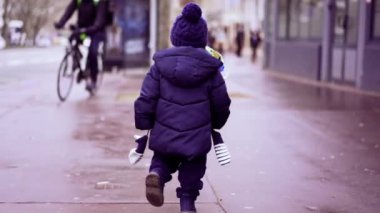 Little toddler running outside in street during winter time