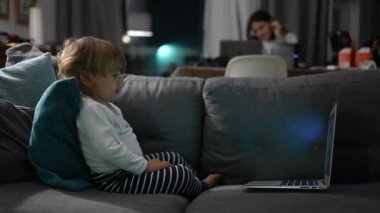 Toddler boy watching cartoon at night sitting in sofa