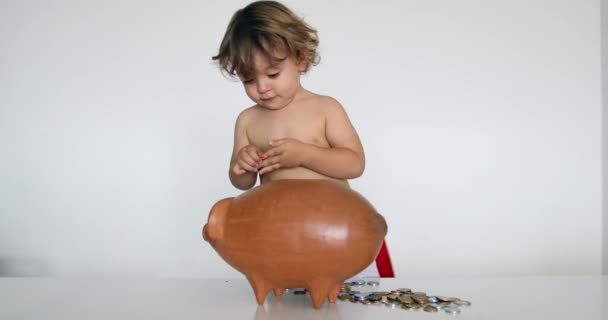 Adorable Baby Boy Adding Savings Piggy Bank — Stockvideo