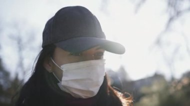 Dışarıda güneş ışığında cerrahi maske takan biri.