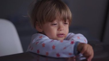 Bashful little baby boy pointing finger at laptop screen watching content
