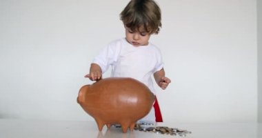 Little boy saving money putting coins inside piggy bank