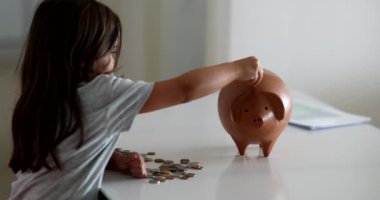 Child adding coins inside piggy bank