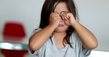 Tired little girl rubbing eyes with hands