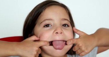 Little girl grimacing, sticking ongue out. Child grimace making funny faces