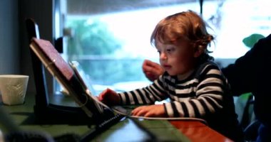 Toddler boy watching cartoon in front of tablet device
