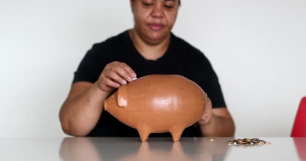 African Woman Inserting Coins Piggy Bank — Vídeo de stock