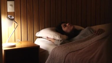 Woman lying in bed unable to sleep, person tossing and turning at night stressed out