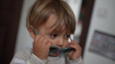 Cute baby toddler removing sunglasses