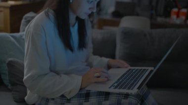 Woman browsing internet at night in front of laptop computer