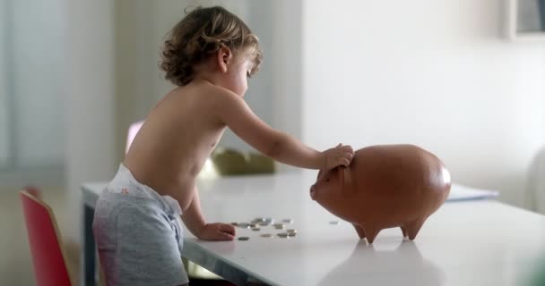 Adorable Baby Boy Adding Savings Piggy Bank — Stok video