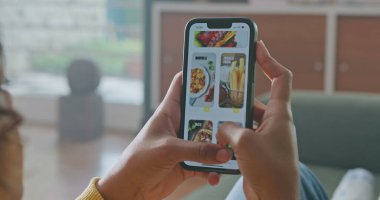 Yakın plan kadın elleri cep telefonlarını tutuyor internette yemek menülerini karıştırıyor. Uygulama aygıtında yiyecek siparişi arayan kişi
