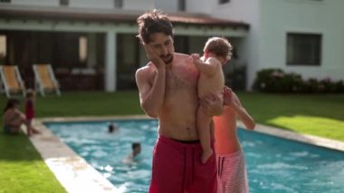 Küçük oğlunu arka bahçede tutarken diş ağrısı çeken bir adam.