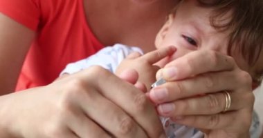 Mother clipping baby hand nails . Infant unhappy upset parent holding trimming nail