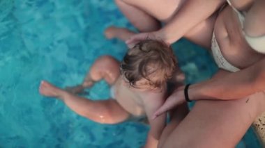 Mother holding one year old infant at swimming pool. Infant and mom seen from above enjoying vacations