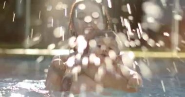 Mother with baby at the swimming pool splashing water with feet