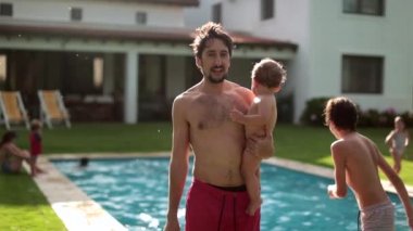 Young dad holding baby son in home backyard. Father holds toddler son outside